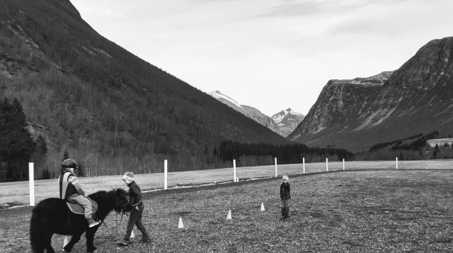 tre-barn-og-ponni-paa-ridebanen
